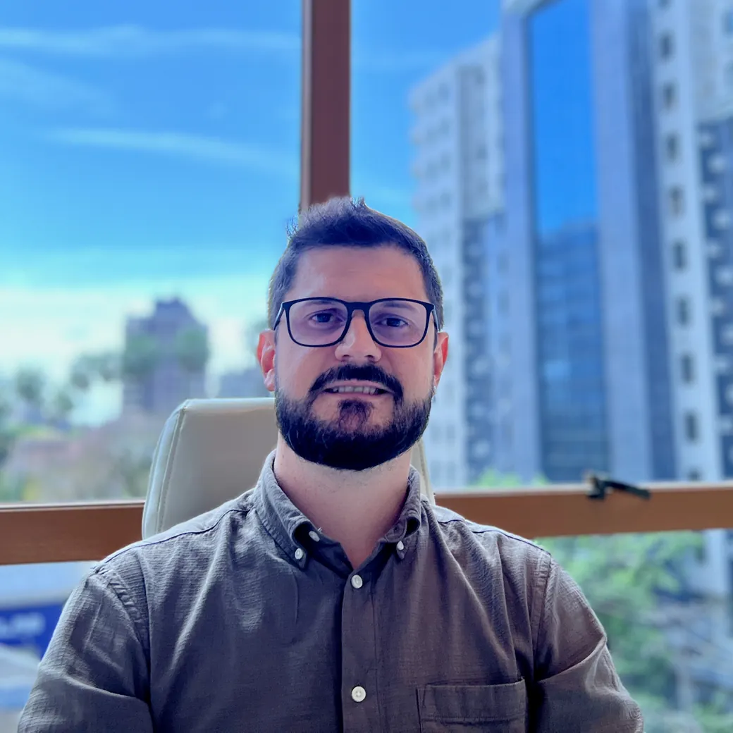 Dr Túlio Peruchi no consultório, com a janela ao fundo.