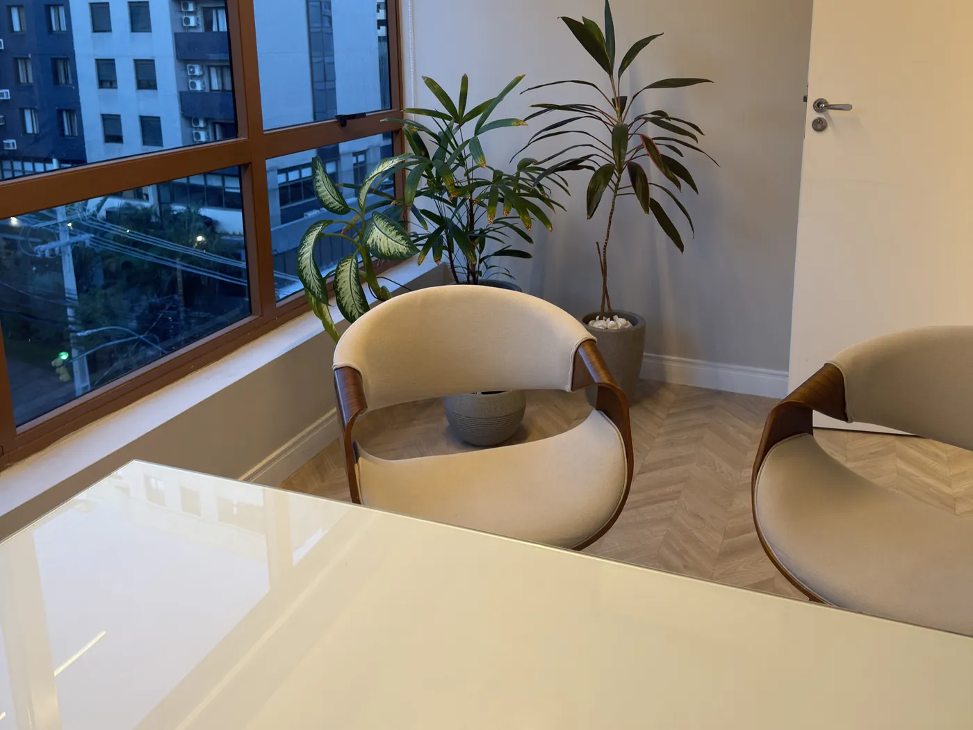 Mesa de espera e poltronas do consultório, com vista da janela ao fundo, em Moinhos de Vento.